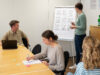 Frau am Flipchart, 3 Personen am Konferenztisch