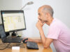 Employee sits at the PC and rests his chin on his hand.