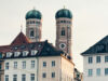 Die Zwillingstürme der Frauenkirche in München über den Dächern historischer Gebäude.