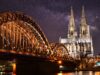 Die beleuchtete Hohenzollernbrücke und der Kölner Dom bei Nacht.